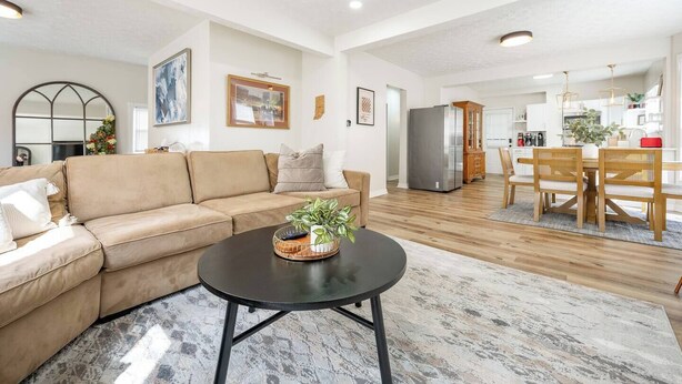 Uma sala de estar moderna com um sofá, uma mesa de centro e uma área de jantar com cadeiras e mesa de madeira.