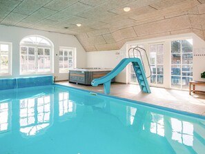 An indoor swimming pool with a slide, large windows, and a hot tub. - 4 Star Holiday Home in Ulfborg (Ulfborg)