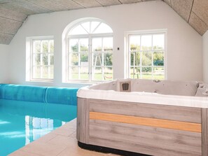 A room with a hot tub, a pool, and a blue sofa. - 4 Star Holiday Home in Ulfborg (Ulfborg)