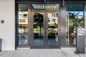 Ein Gebäudeeingang mit einem Schild, auf dem '2301 E UNION' steht, und eine Glastür, die einen Straßenblick reflektiert.