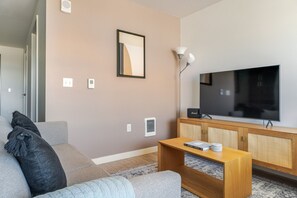 Ein Wohnzimmer mit Sofa, Couchtisch, Fernseher und Lampe.