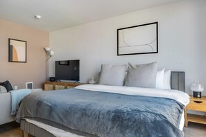 Ein modernes Hotelzimmer mit einem großen Bett, einem Fernseher, einem Nachttisch und einem Wandbild.