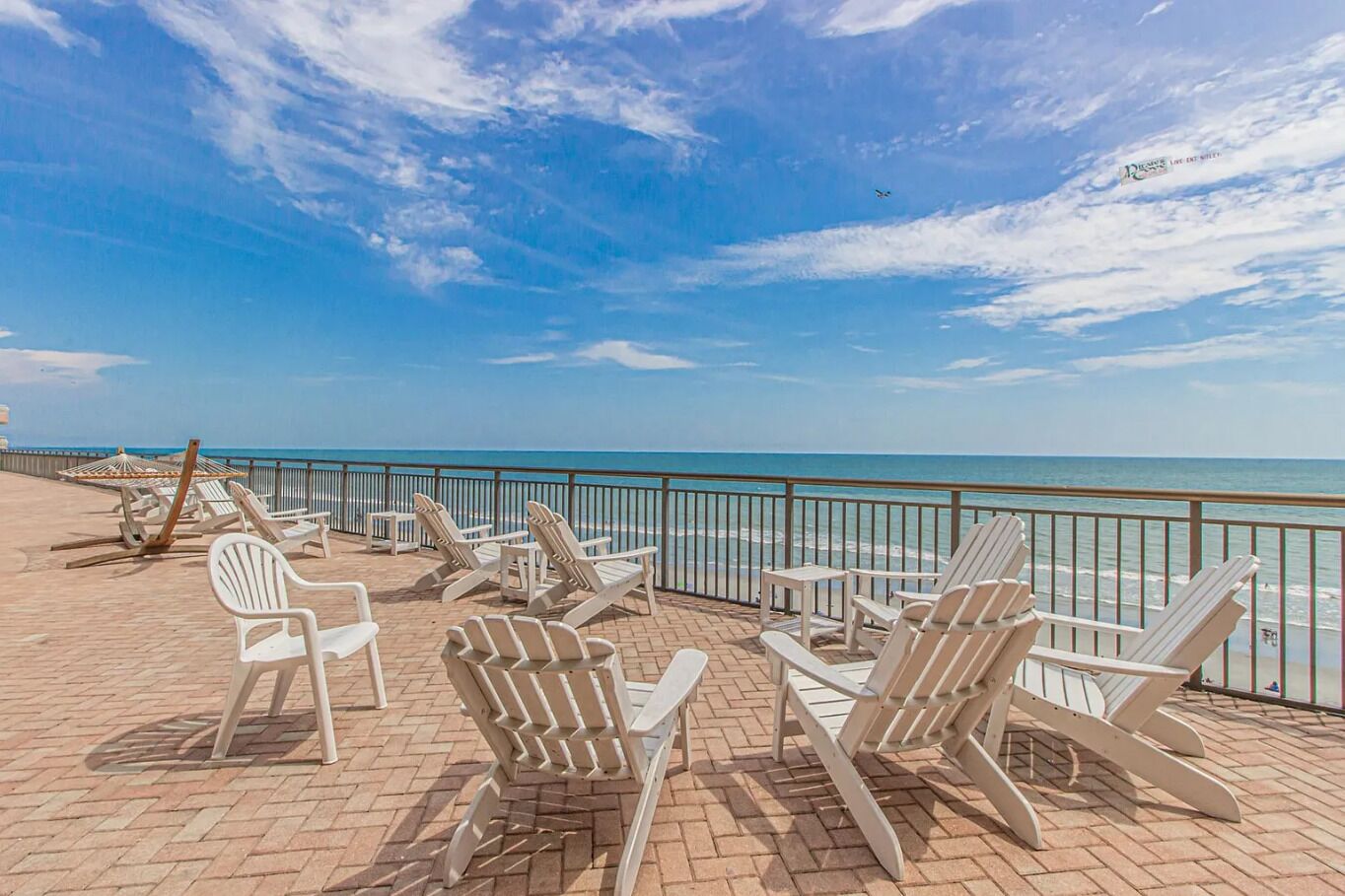 A beachside lounge with white lounge chairs and umbrellas, overlooking the ocean.