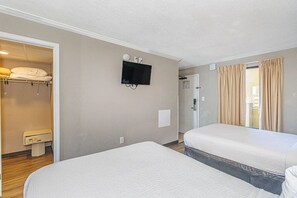 Ein Hotelzimmer mit zwei Betten, einem Fernseher, einem Badezimmer mit Dusche und Blick ins Freie.