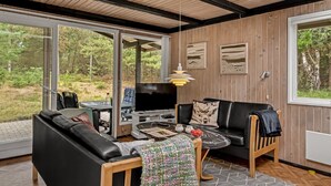 Ein modernes Wohnzimmer mit einem schwarzen Ledersofa, einem Holztisch und einem Fernseher.