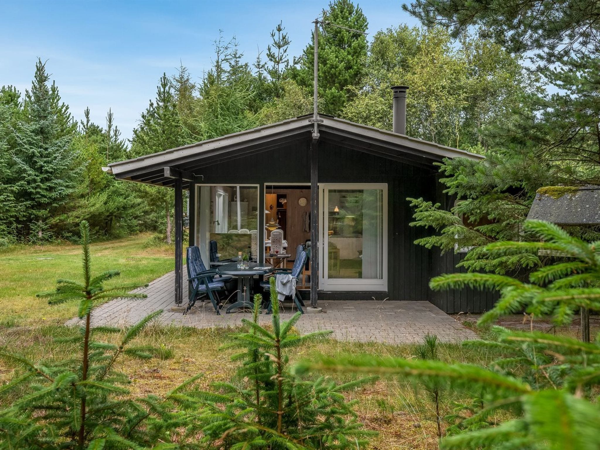 A modern cabin with a patio area, a dining table, and chairs.
