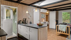 Eine moderne Küche mit Holzelementen, einer zentralen Kochinsel, Pendelleuchten und Blick ins Freie.