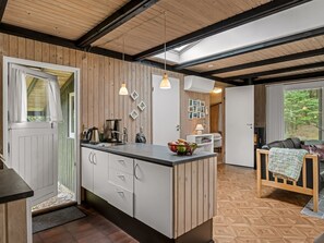 A modern kitchen with wooden accents, a central island, pendant lighting, and a view of the outdoors. - "Hardina" - 1km from the sea by Interhome (Vejers Strand)