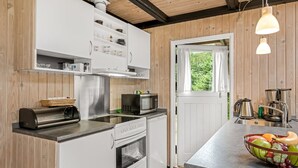 Eine moderne Küche mit weißen Schränken, Edelstahlgeräten und einer Holzbalkendecke.