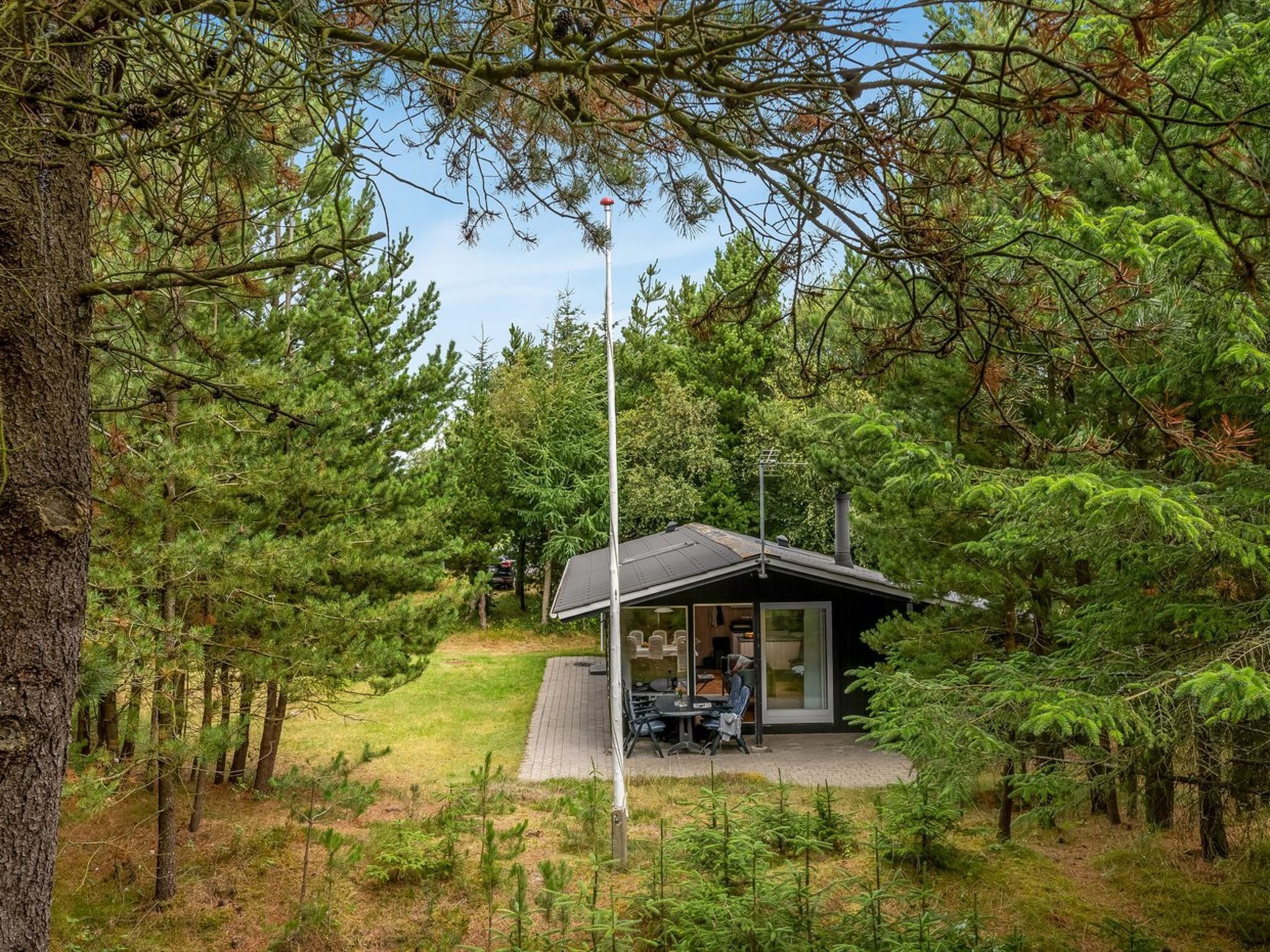 Eine Hütte mit kleiner Terrasse, umgeben von dichtem Wald.