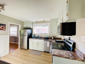 A kitchen with white cabinets, stainless steel appliances, a window, and a microwave. - Peaceful 4-bedroom ranch in Richmond’s west end. (Richmond)
