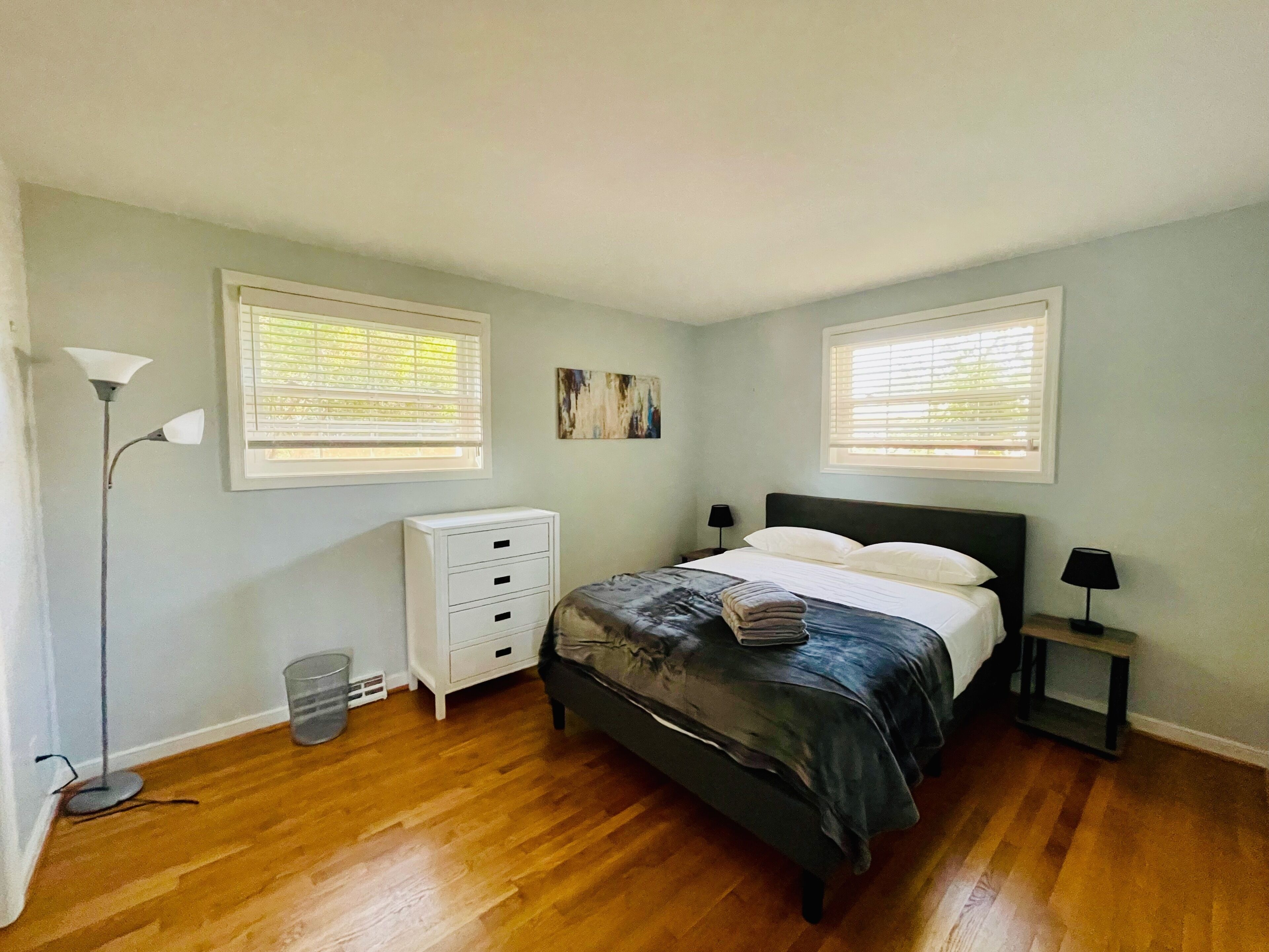 Un dormitorio con cama, mesitas de noche, una lámpara de pie y un aparador.