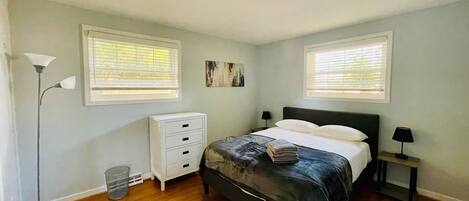 Une chambre à coucher comprenant un lit, des tables de chevet, une lampe sur pied et une commode.