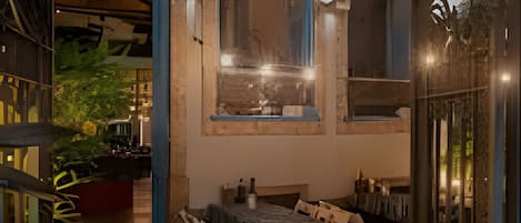 Un espace extérieur aménagé avec une table et des chaises, une grande fenêtre et un mur décoratif agrémenté d’une horloge.