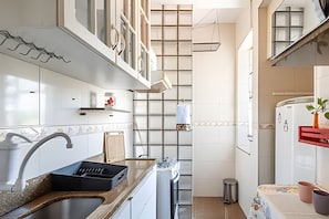 A modern kitchen with white cabinets, a stainless steel sink, and a built-in oven. - Perto da Praia - Botafogo - HOTSPOT (Rio de Janeiro)