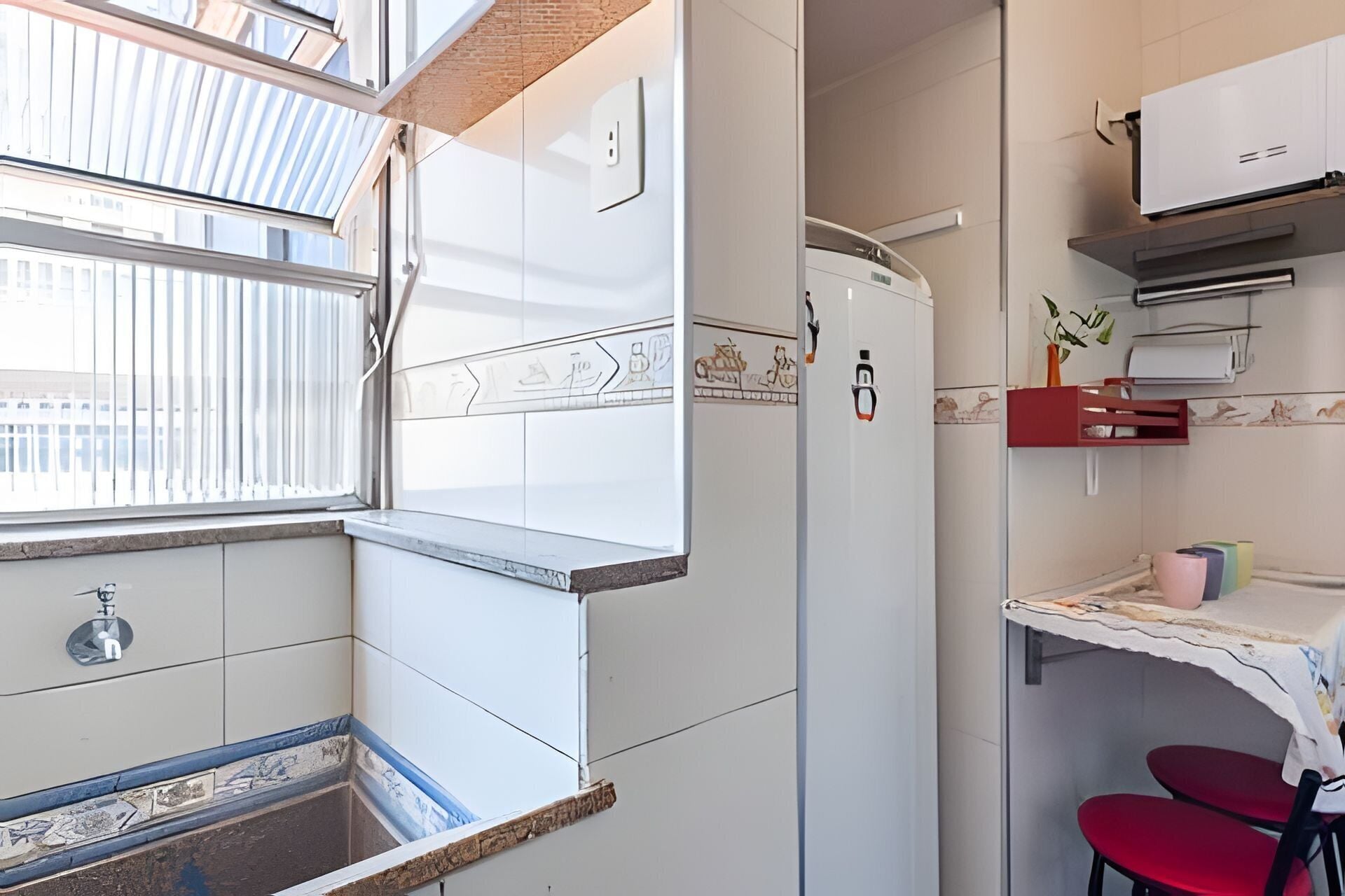 Una cocina compacta con horno integrado, refrigerador y un pequeño comedor con una mesa y dos sillas.