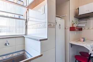 A compact kitchen with a built-in oven, a refrigerator, and a small dining area with a table and two chairs.