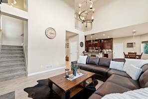 Ein geräumiges Wohnzimmer mit einer großen braunen Ledersofa, einem Holztisch und einer Treppe, die zu einer oberen Ebene führt.