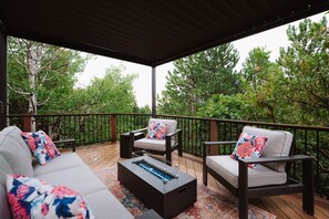Eine Terrasse im Freien mit einer Couch, zwei Stühlen und einem Couchtisch.