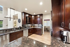 Eine moderne Küche mit Granit-Arbeitsplatten, Edelstahlgeräten und dunklen Holzschränken.