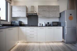 A modern kitchen with white cabinets, a built-in oven, a microwave, and a refrigerator. - Cozy 2-bedroom apartment in peaceful Pereybere (Grand Baie)