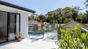 Una casa moderna con balcón de vidrio, piscina y jardín.