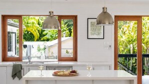 Una cocina moderna con una isla central, dos lámparas colgantes y vistas al exterior.