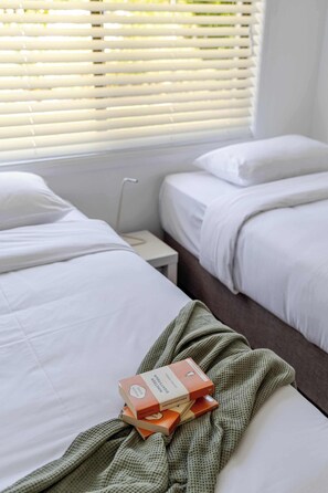 Ein Hotelzimmer mit zwei Betten, einem Nachttisch und einem Fenster mit Jalousien.