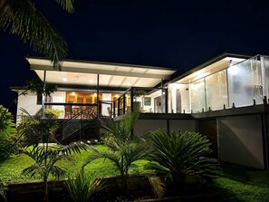 Una casa moderna con un espacio exterior cubierto, una escalera y un jardín cuidado.
