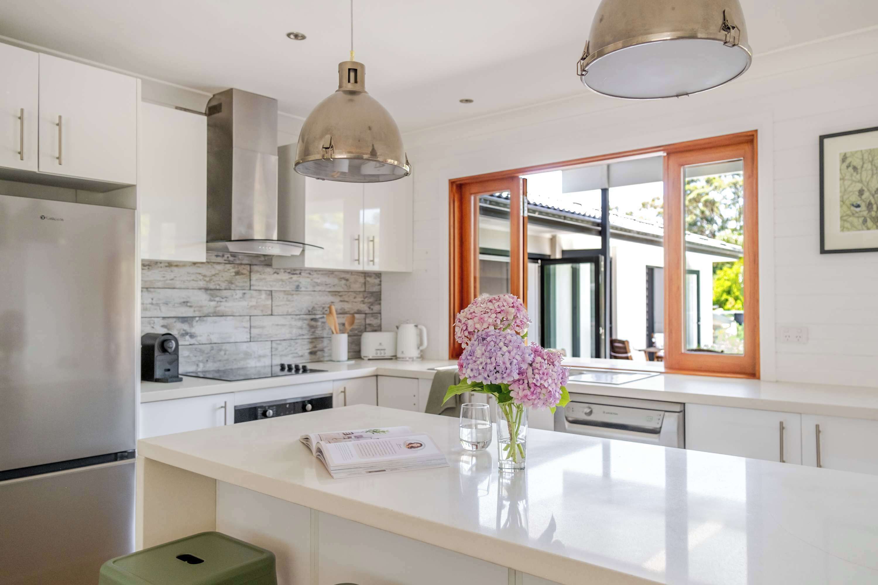 Una cocina moderna con armarios blancos, salpicadero de mármol y electrodomésticos de acero inoxidable.