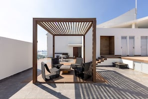 Une terrasse sur le toit agrémentée d’une pergola en bois, de sièges d’extérieur et offrant une vue sur le panorama urbain.