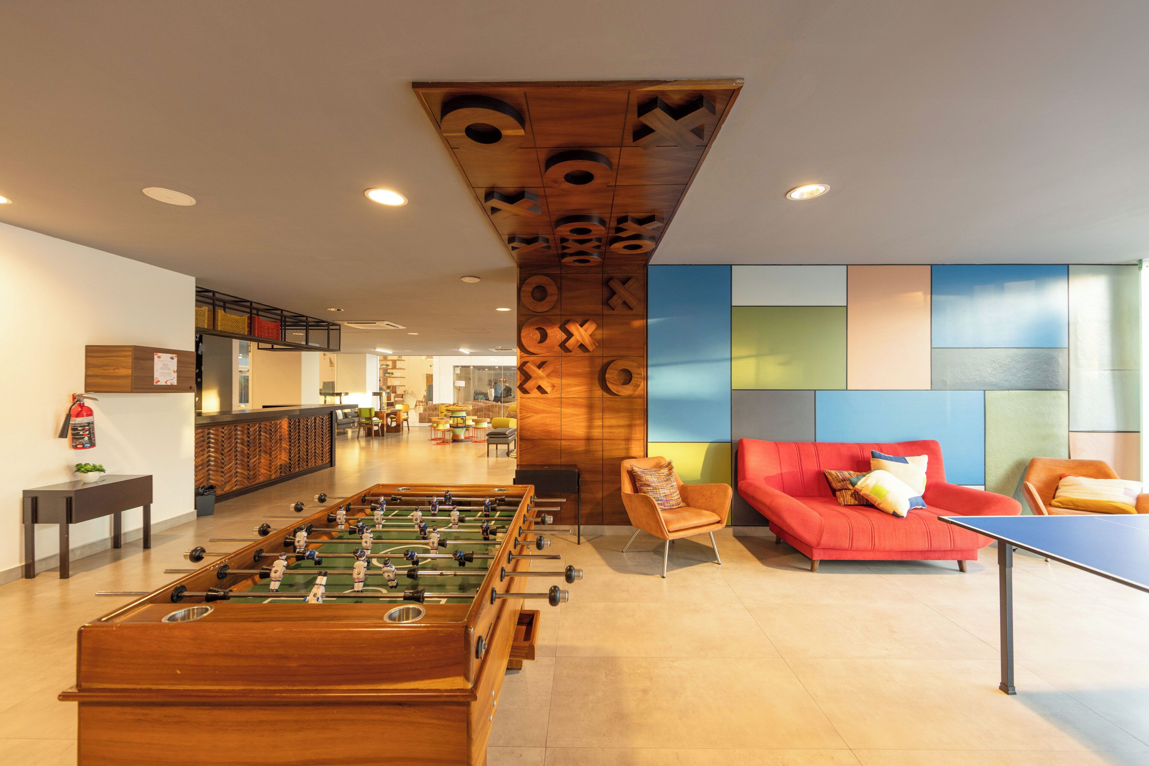 A modern lobby with a foosball table, a red sofa, and a colorful wall design.