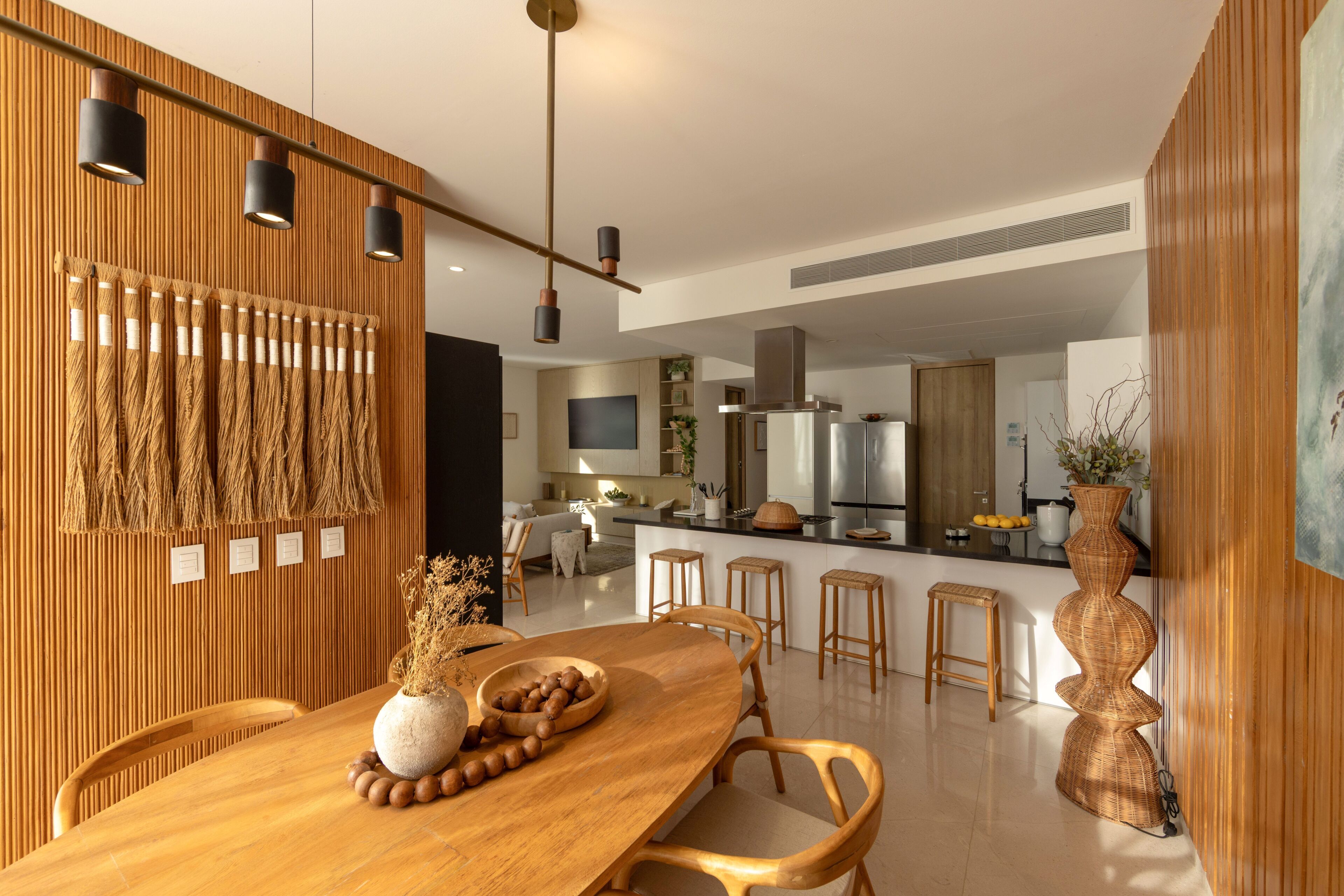 Une cuisine moderne équipée d’appareils électroménagers en acier inoxydable, un coin repas en bois avec une grande table et un bar avec des tabourets.
