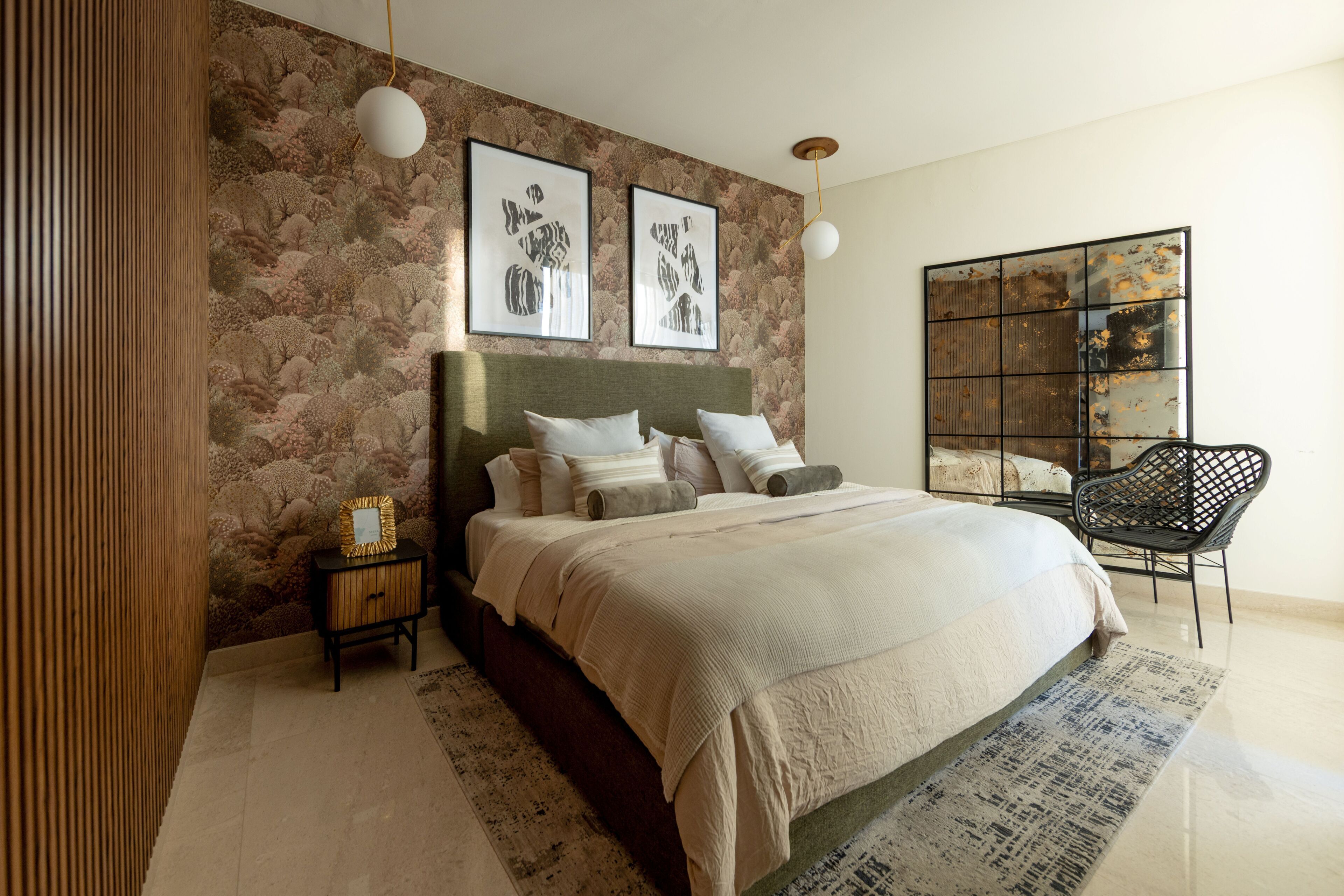 Quarto com uma cama grande, uma mesinha de cabeceira, uma cadeira e duas luminárias fixadas na parede.