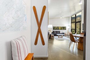 Un intérieur moderne agrémenté d’une grande sculpture en bois en forme de X, d’une carte, d’un canapé, d’un coin repas et d’un téléviseur.