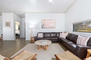 Ein modernes Wohnzimmer mit einem dunkelbraunen Ledersofa, einem runden Couchtisch und einem großen Fenster mit Aussicht.