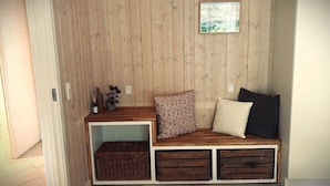 Eine Holzbank mit Stauraumschubladen und einem kleinen Regal, ein gerahmtes Bild an der Wand und ein Topfpflanze.
