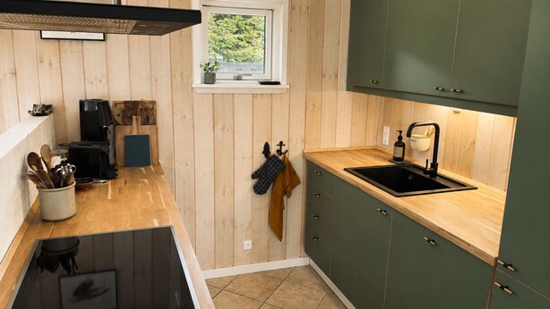 Eine kleine Küche mit Holzwänden, einem Fenster und einem Spülbecken.