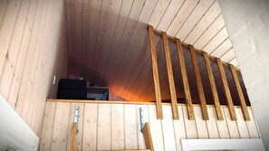 Ein Holzinnenraum mit schräg angelegter Decke und einer Holztreppe.