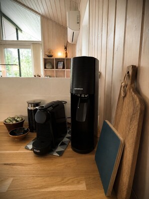 Eine moderne Küche mit einer Kaffeemaschine, einem schwarzen Wasserspender und einem Schneidebrett, das an der Wand lehnt.