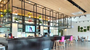 Uma área de bar moderna com balcão, banquetas e uma tela de televisão.