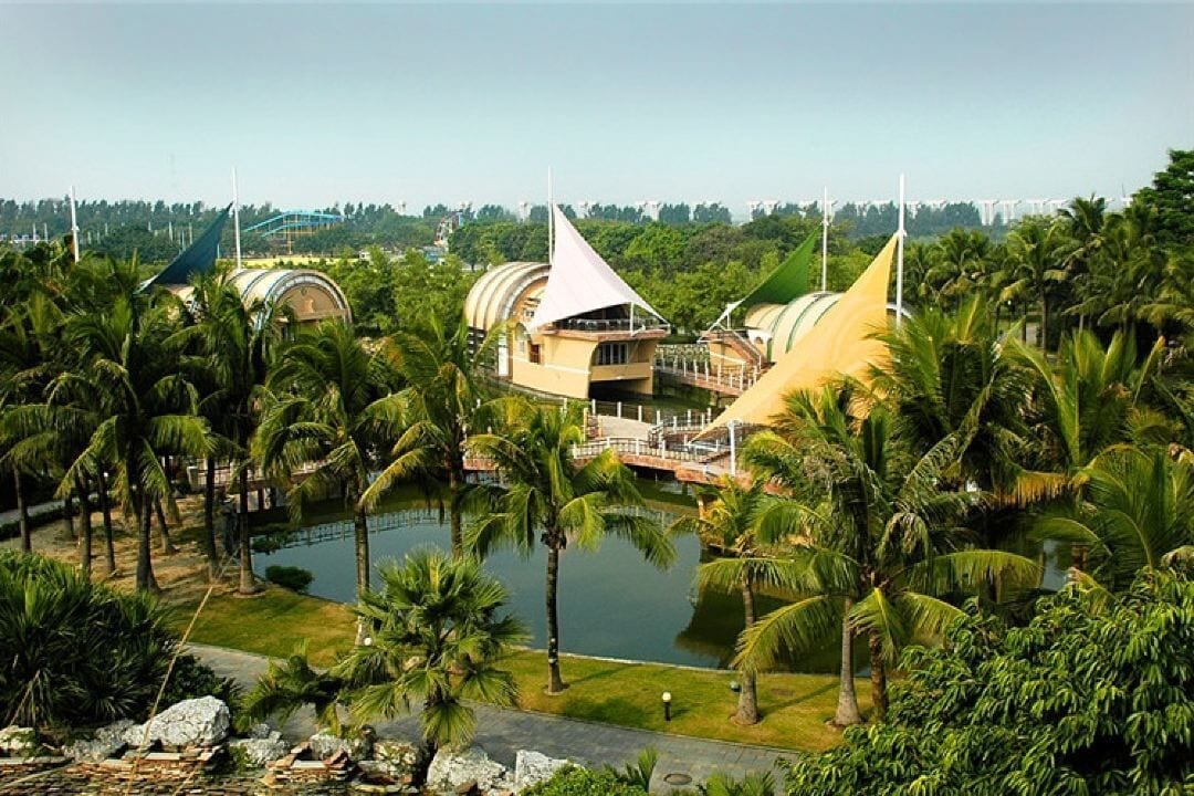 A resort with a large pool surrounded by palm trees and a building with a unique architectural design.