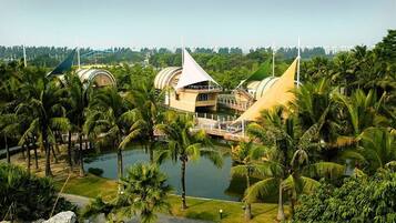 A resort with a large pool surrounded by palm trees and a building with a unique architectural design.