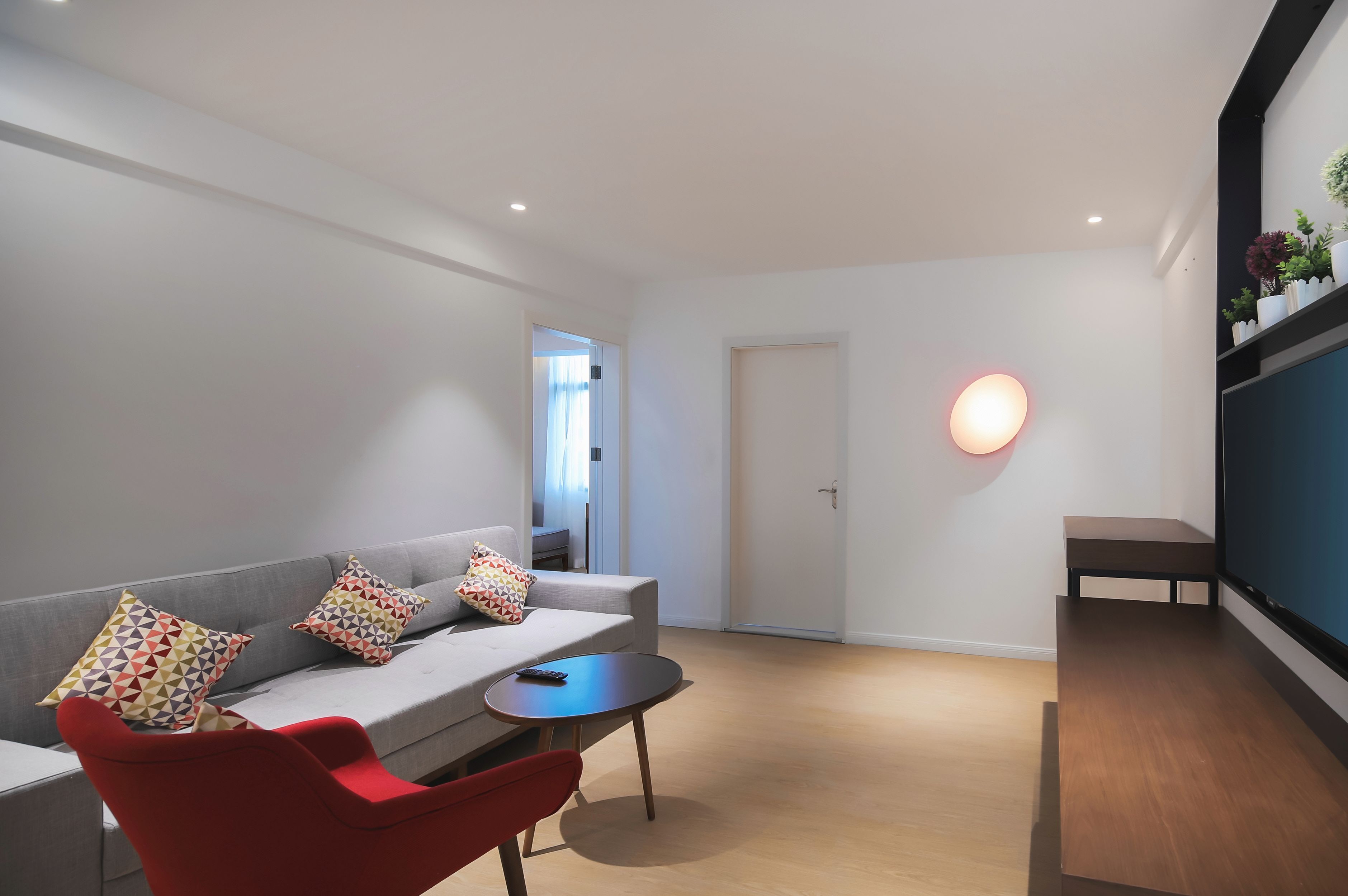 A modern living room with a grey sofa, red chair, and a small round table.