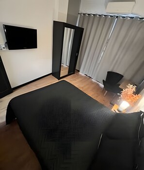 Una habitación de hotel moderna con una cama, un televisor de pantalla plana en la pared, un escritorio y una silla.