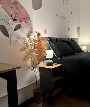 Un dormitorio con cama, mesita de noche, lámpara y una pared decorada con arte abstracto.