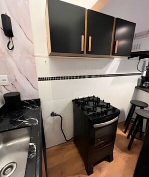 Una cocina con gabinetes negros, encimera de mármol y salpicadero de azulejos.