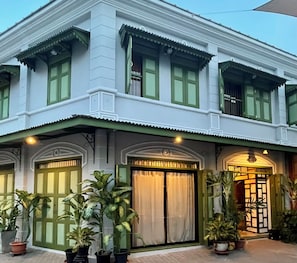 A two-story building with green-framed windows and doors, a tiled roof, and potted plants in front. - Welcome to Chur’s Garden Boutique Stay 100-Year-Old Heritage Chinatown Bangkok (Krung Thep Maha Nakhon)