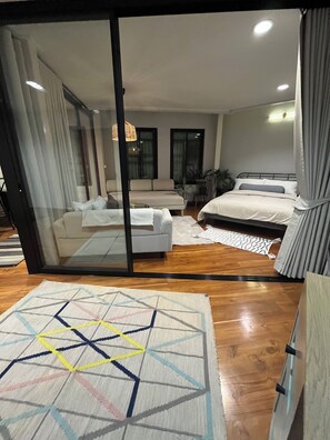 A modern bedroom with a glass door leading to a balcony, a bed, a sofa, and a small table. - Welcome to Chur’s Garden Boutique Stay 100-Year-Old Heritage Chinatown Bangkok (Krung Thep Maha Nakhon)