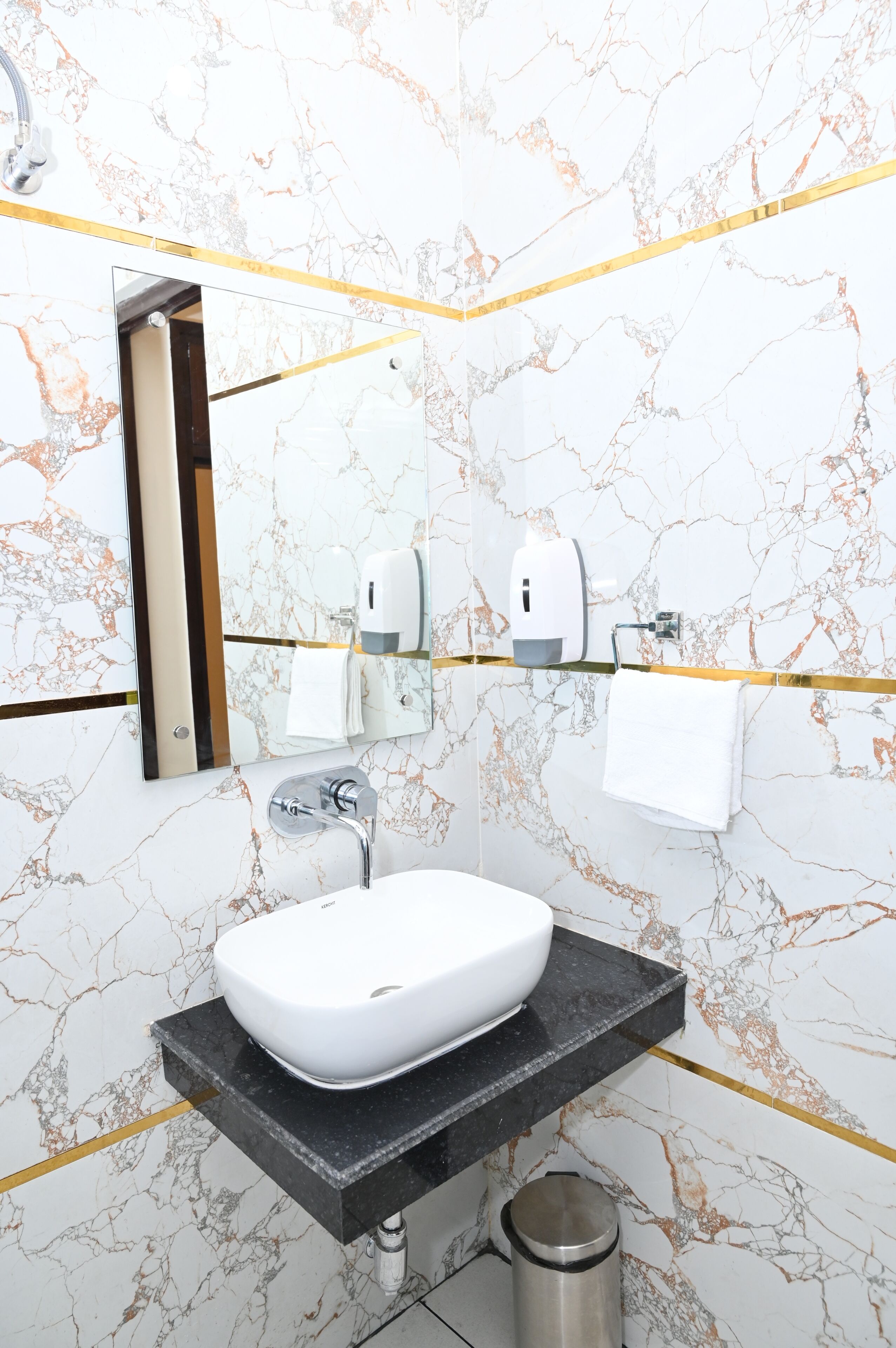 Un baño con lavamanos blanco, un espejo y un perchero para toallas.